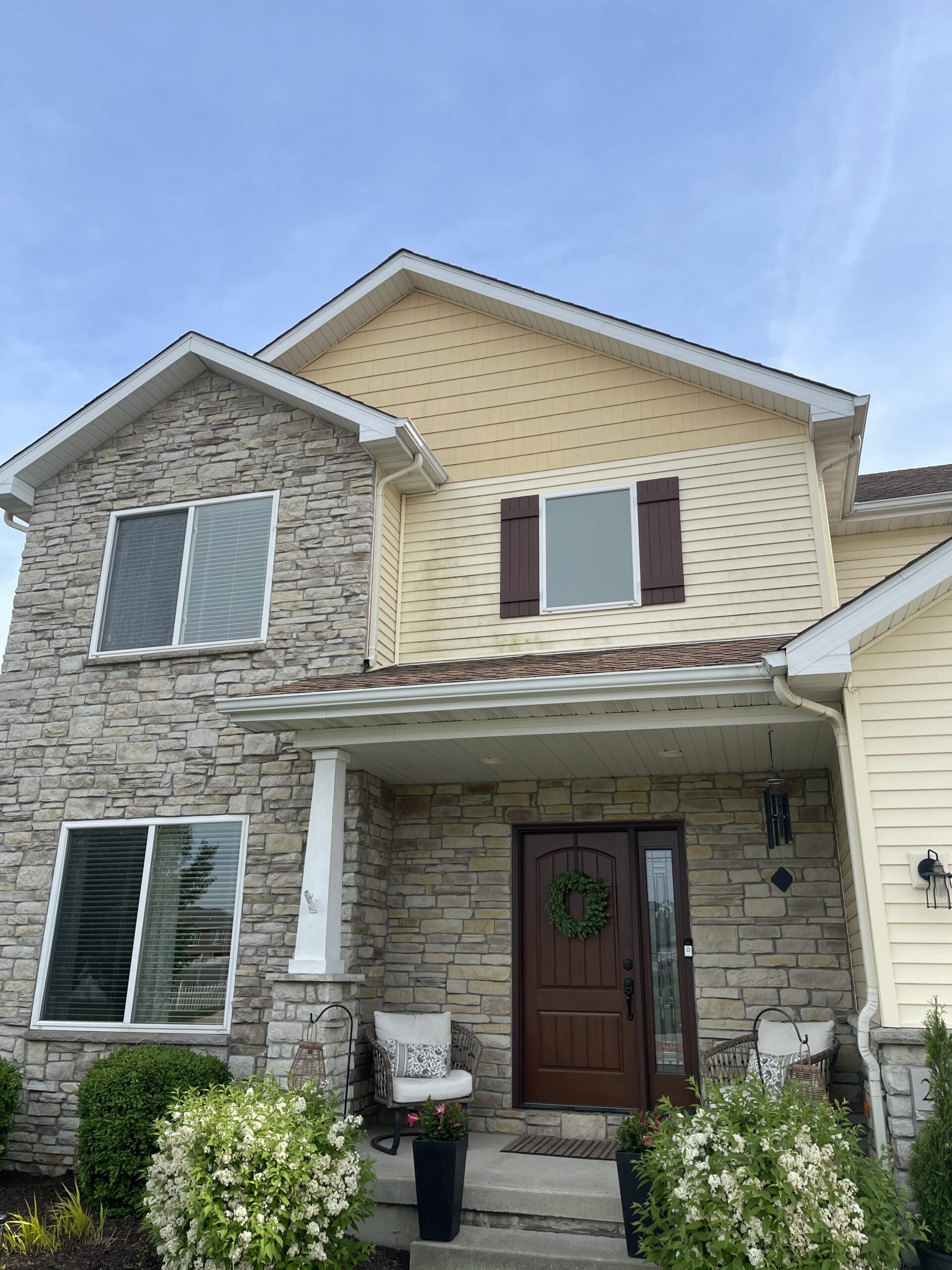 Roof cleaning specialist inspecting shingle staining and organic buildup with safety equipment