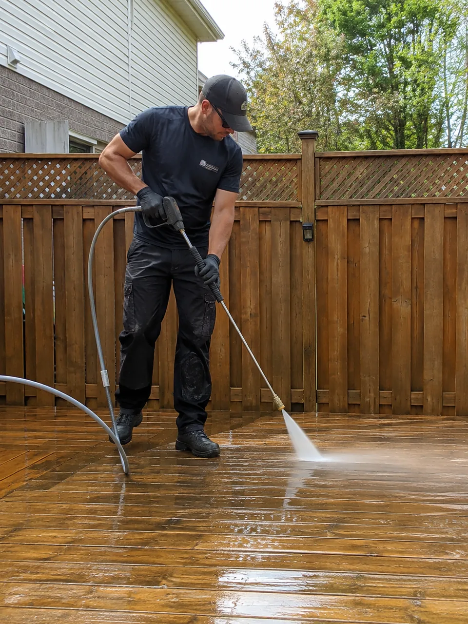 Technician pressure washing a stained walkway beside a Lake County - IN home entrance