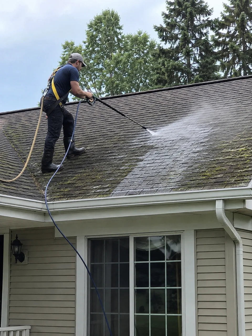 Roof Washing in Valparaiso - IN in progress as a technician treats black streaks on shingles